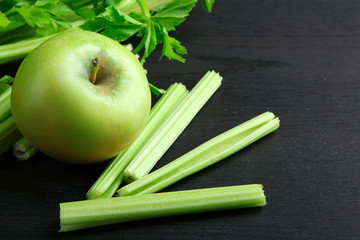 Fresh green celery on wooden background black with green Apple