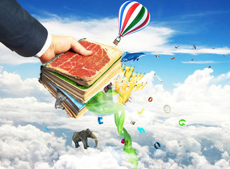 Concept of reading. Man's hand holding magic book with falling l