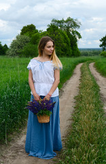 Young woman with basket of meadow flowers on rural road