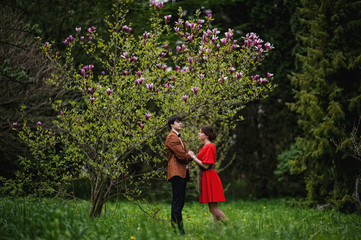 Naklejka na ściany i meble Couple hugging in love near magnolia tree. Stylish man at velvet