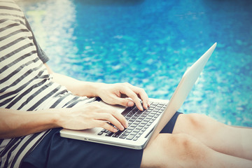 Man using a laptop in the pool on vacation - work anywhere and internet work concept