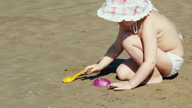 Cute little kid playing on the beach near the sea.