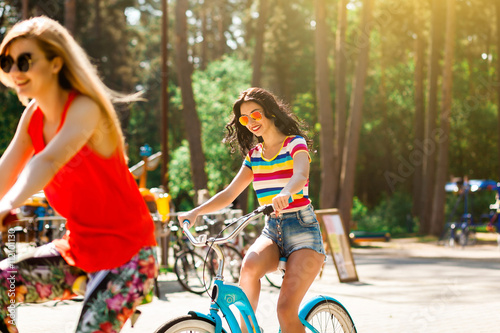 Two Beautiful Tanned Slim Sexy Hipster Girls Engaged In Outdoor Sports Riding Bikes Laughing Two Beautiful Tanned Slim Sexy Hipster Girls Engaged In Outdoor Sports Riding Bikes Laughing
