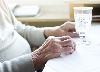 Senior woman's hands with glass of water
