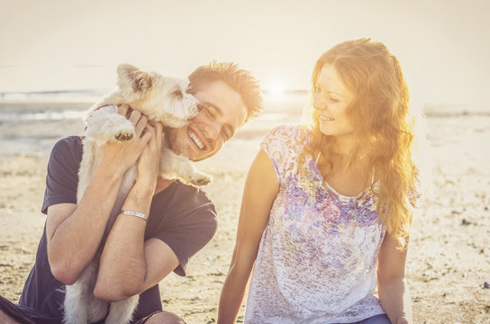Loving couple playing with dog at the beach