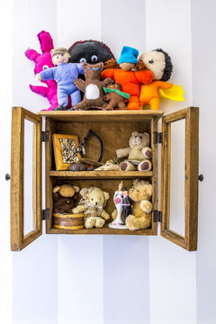 Old rustic wall mounted wood display cabinet stuffed with items and toys. 