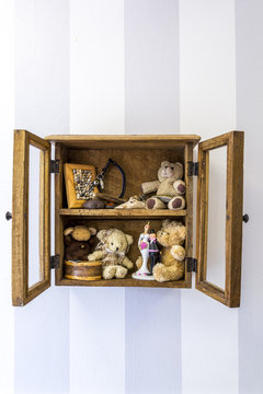 Old rustic wall mounted wood display cabinet stuffed with items and toys, vertical. 