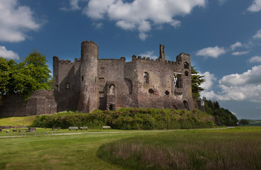 Fototapeta na wymiar Laugharne Castle, a medieval castle on the river Taf estuary in Carmarthenshire, South Wales, with Dylan Thomas's Boat House tucked away to the right. 