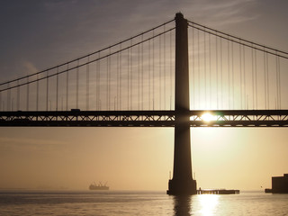 Fototapeta na wymiar Sunrise over San Francisco Bay and through the Bay Bridge with b