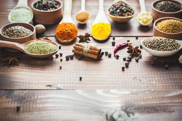 Beautiful colorful spices in wooden spoons on an old wooden brown table. Free space for your text