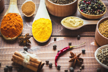 Beautiful colorful spices in wooden spoons and bowls on an old wooden brown table.