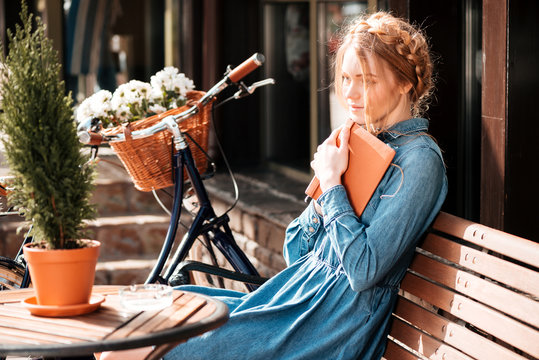 Thoughtful woman readng book and dreaming on the beanch outdoors