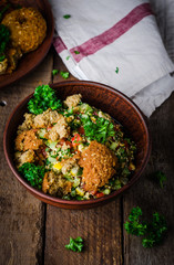 Fresh tabbouleh with falafel - a Middle Eastern salad, in clay bowl on wooden background. Selective focus. Toned image. Ramadan food