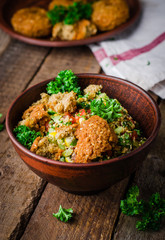 Fresh tabbouleh with falafel - a Middle Eastern salad, in clay bowl on wooden background. Selective focus. Toned image. Ramadan food