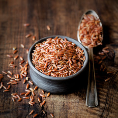 Red rice an a small ceramic bowl against dark rustic wooden background