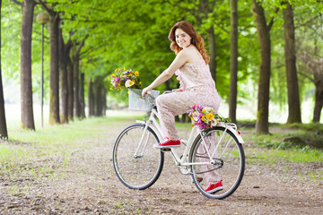 Obraz premium Beautiful young woman standing with a vintage bicycle at the par