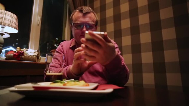 Man Drinking Beer In Pub And Serfing Smartphone