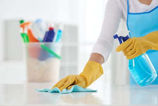 Cropped image of housewife wiping table with spray