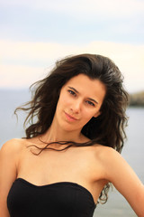 Fototapeta na wymiar Beautiful slim brunette girl model posing in fashion dress by the sea