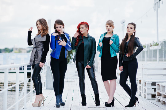 Five beautiful young girls models at leather jackets posing on b