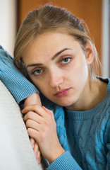 Upset girl in pullover feeling lonely at home