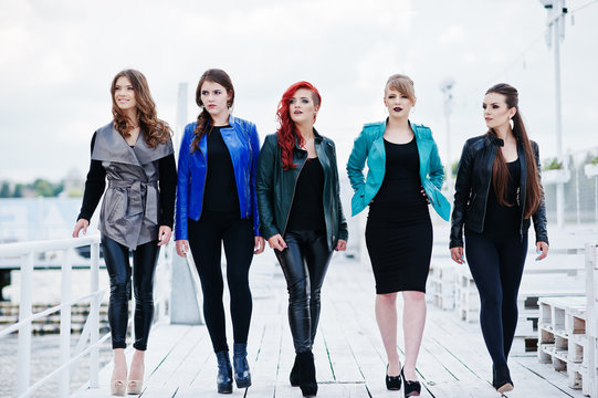 Five beautiful young girls models at leather jackets posing on b