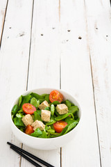 Vegan tofu salad in bowl on white wood
