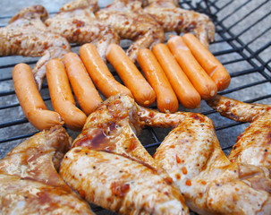 Fresh sausage and chicken grilling outdoors on a gas barbecue grill