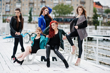 Five beautiful young girls models at leather jackets posing on b