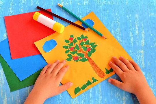 Child made an apple tree, clouds, grass out of paper. Easy and fun craft for kids: torn paper collage. Paper tree ornament. Summer activities for kindergarten. Hand applique tutorial
