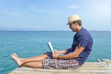 Man sitting on the dock reading a book