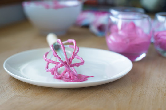 Wire whisk with pink mixed berry mousse on it. Selective focus.