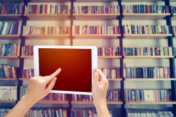 woman hand using the phone tablet with book shelf background