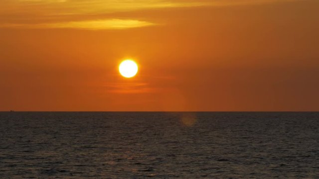 A beautiful yellow/orange sunset with a fiery sky over the ocean in Mai Khao, northern Phuket in Thailand. Filmed in 4k UHD resolution from the Mai Khao paradise beach.