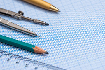 drawing compass, pencil, and ruler on graph paper background
