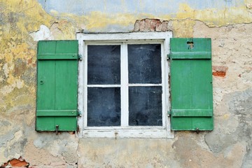 Fototapeta na wymiar Altes Holzfenster mit offenen Schlagläden in einem verfallenen, sanierungsbedürftigen Haus