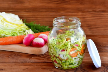 Fresh cabbage salad with carrot and radishes. Healthy vegetable salad. Salad in a glass jar. Vegetable diet food. Cabbage, radishes, carrots, dill - organic ingredients. Cooking healthy vitamin food