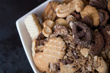 Mix of different sweet cookies in a white plate on black background