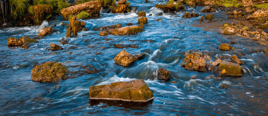 small mountime river.A pair of river rocks with a small waterfall