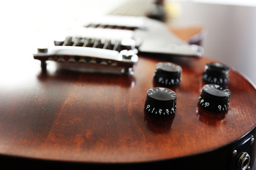 Brown electric guitar on black wooden background, close up