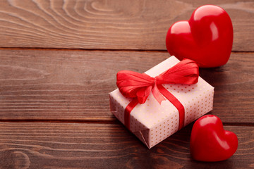 Gift box and decorative hearts on wooden background