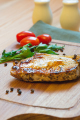 Juicy grilled pork chop (neck cut) on cutting board.