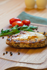 Juicy grilled pork chop (neck cut) on cutting board.