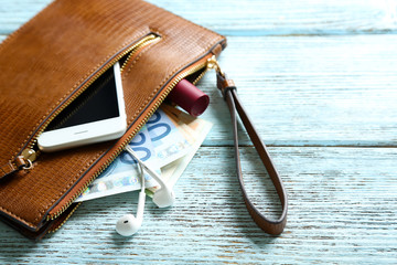 Leather purse with mobile phone and euro banknotes on wooden background