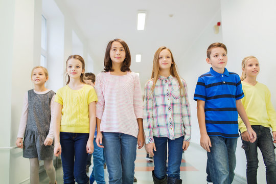 Group Of Smiling School Kids Walking In Corridor