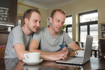 smiling gay couple doing online banking on his laptop