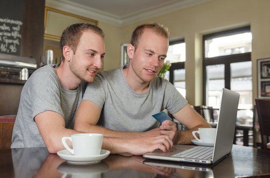 Smiling Gay Couple Doing Online Banking On His Laptop