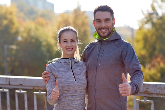 smiling couple showing thumbs up outdoors