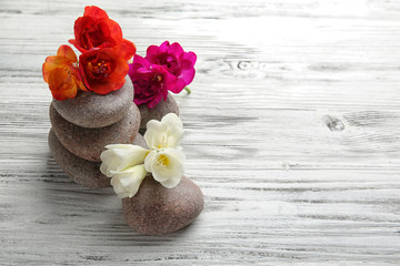 Spa stones for therapy with flowers on white wooden background