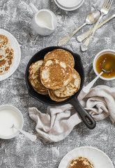 Whole grain pancakes in a cast iron pan on a stone background. Breakfast table